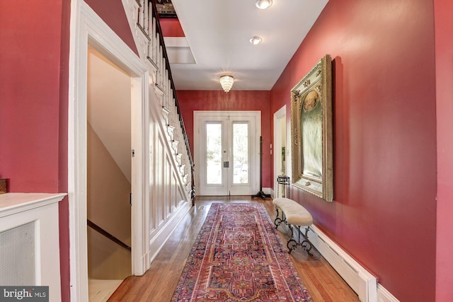 entryway with french doors, a baseboard heating unit, and light wood finished floors