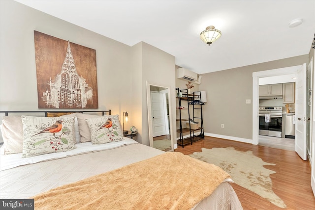 bedroom featuring wood finished floors, baseboards, and a wall mounted AC