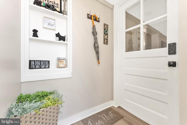 doorway featuring baseboards and wood finished floors