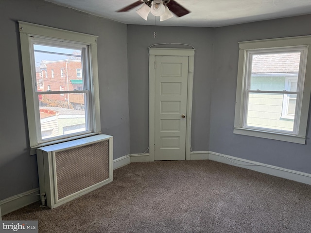 spare room featuring carpet floors, ceiling fan, baseboards, and radiator heating unit