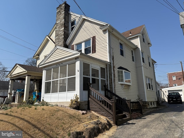 view of front of house featuring a chimney and a sunroom