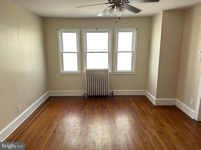 unfurnished room featuring dark wood-type flooring, a ceiling fan, plenty of natural light, and radiator heating unit