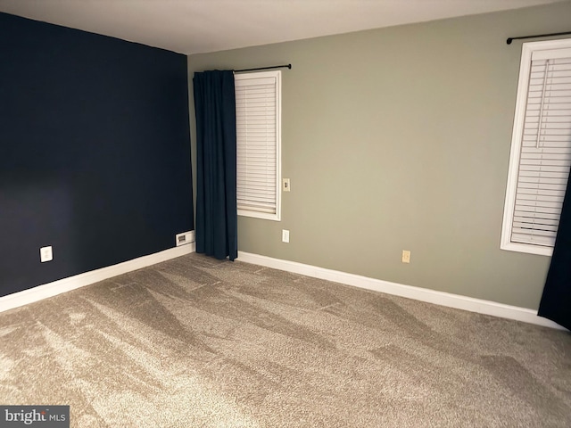 empty room featuring carpet floors and baseboards