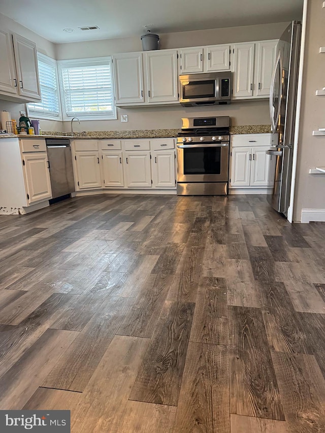 kitchen featuring white cabinets, stainless steel appliances, dark wood finished floors, and visible vents