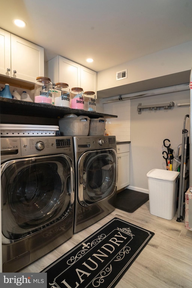 washroom with visible vents, washing machine and dryer, wood finished floors, recessed lighting, and cabinet space