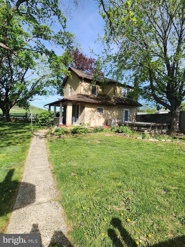 view of side of property with fence and a yard