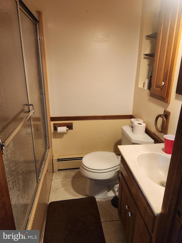 bathroom featuring tile patterned flooring, vanity, a baseboard heating unit, toilet, and shower / bath combination with glass door