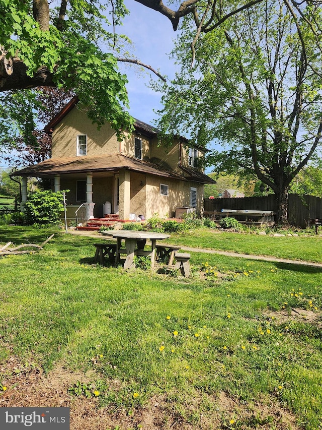 back of property featuring a lawn, fence, and stucco siding