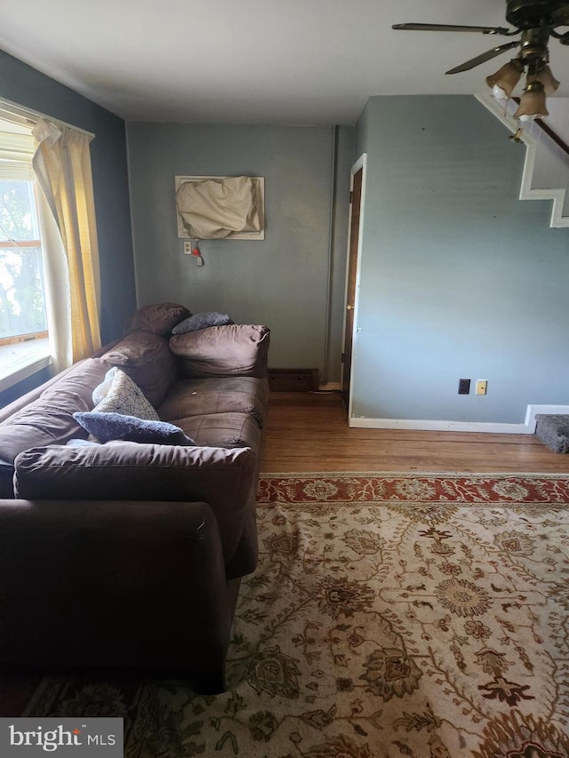 living room featuring baseboards, ceiling fan, and wood finished floors