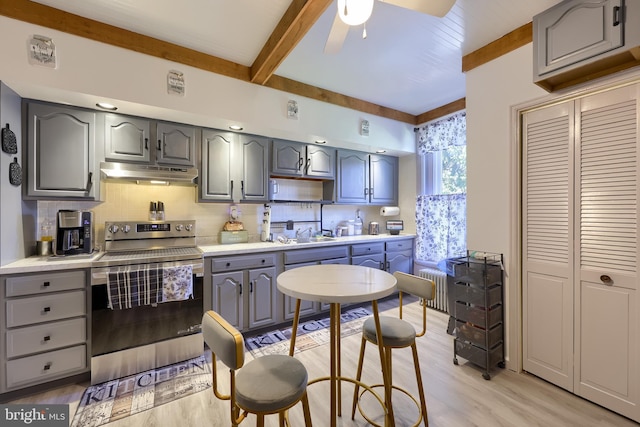 731 Locust St, Columbia, PA 17512 - kitchen featuring stainless steel electric range oven, gray cabinetry, beamed ceiling, radiator heating unit, and under cabinet range hood