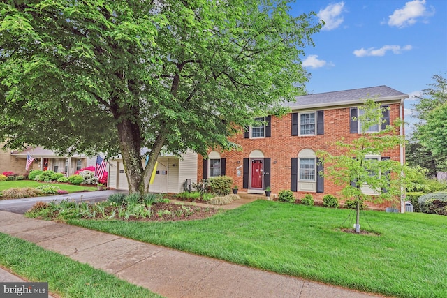 colonial inspired home featuring brick siding, an attached garage, driveway, and a front lawn