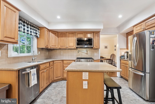 kitchen with a kitchen island, a breakfast bar, tasteful backsplash, a sink, and appliances with stainless steel finishes