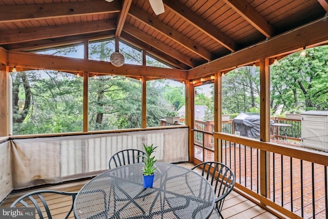 sunroom with beamed ceiling, a ceiling fan, and outdoor dining space
