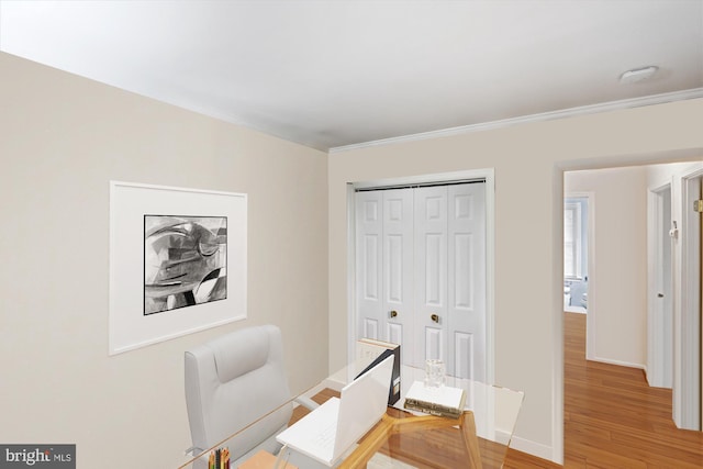 office space featuring baseboards, ornamental molding, and light wood-style flooring