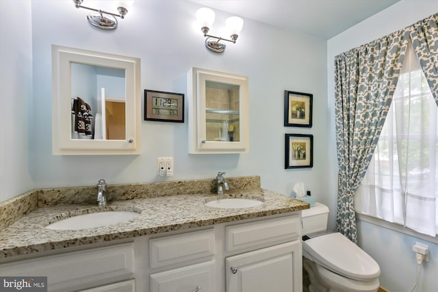 full bathroom with double vanity, toilet, an enclosed shower, and a sink