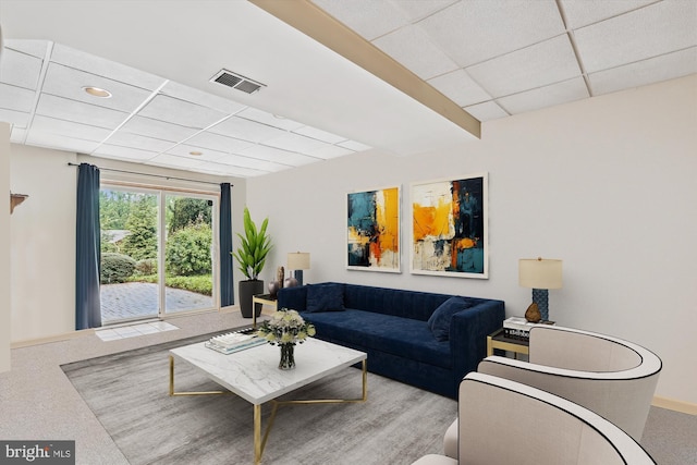 carpeted living room featuring visible vents, baseboards, and a drop ceiling