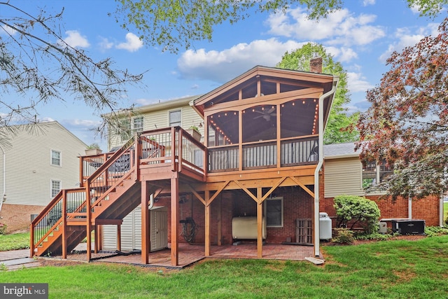 back of property featuring heating fuel, a chimney, stairs, a sunroom, and a lawn