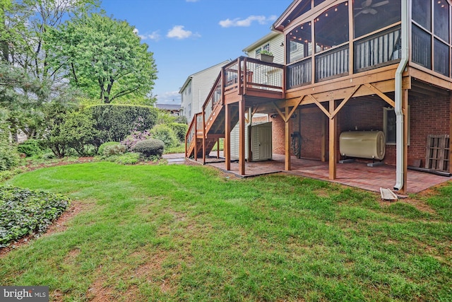 back of property with stairs, a wooden deck, heating fuel, a patio area, and a yard
