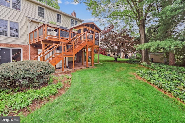 rear view of house with a lawn, a wooden deck, a chimney, and stairway