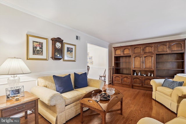 living area featuring visible vents, ornamental molding, and light wood finished floors