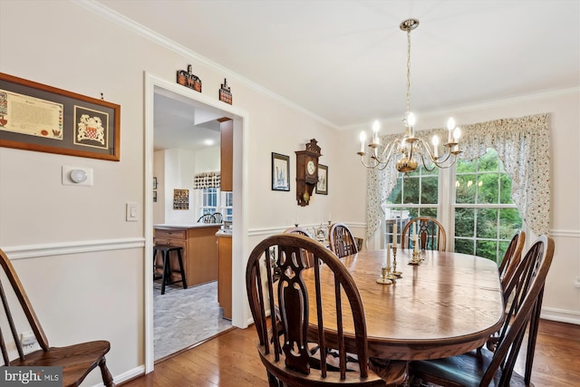dining room with ornamental molding, wood-type flooring, and a chandelier