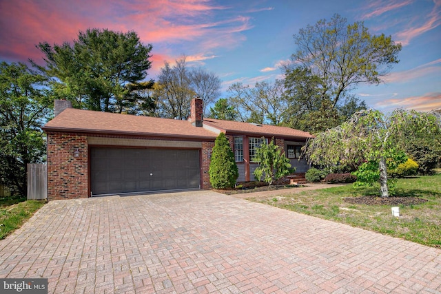 single story home with brick siding, a chimney, decorative driveway, and a garage