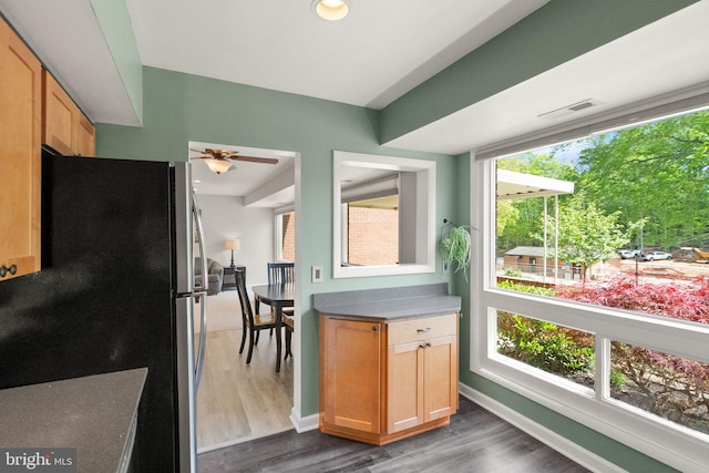 interior space featuring visible vents, freestanding refrigerator, wood finished floors, baseboards, and ceiling fan