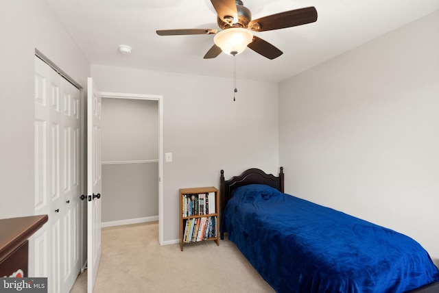 bedroom featuring a ceiling fan, baseboards, light colored carpet, and a closet