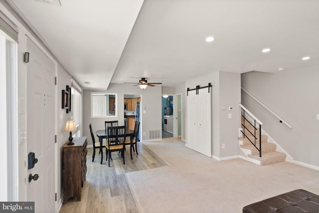 interior space featuring a ceiling fan, baseboards, a barn door, and stairway