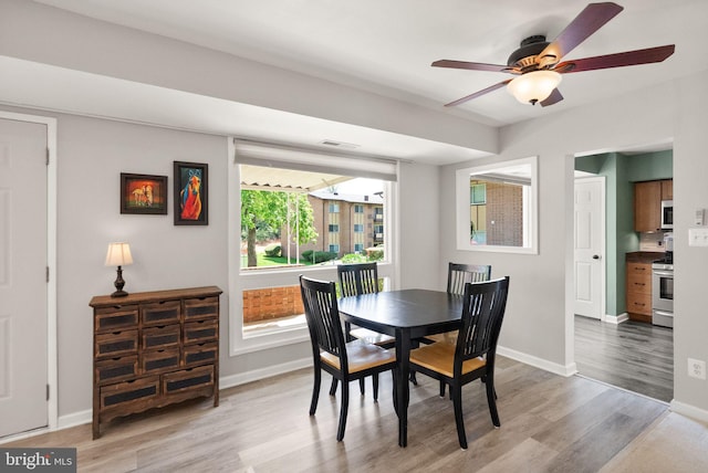 dining space with light wood-style floors, baseboards, ceiling fan, and visible vents
