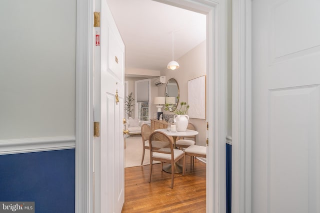 hall featuring a wall unit AC and wood finished floors