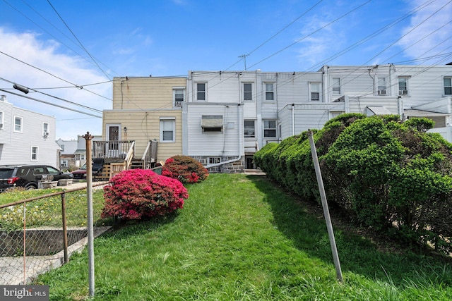 back of house featuring a lawn, fence, and a residential view