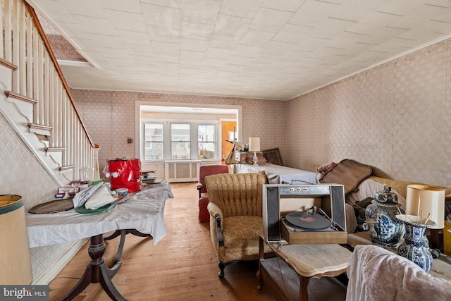living area featuring crown molding, wood finished floors, stairway, and wallpapered walls