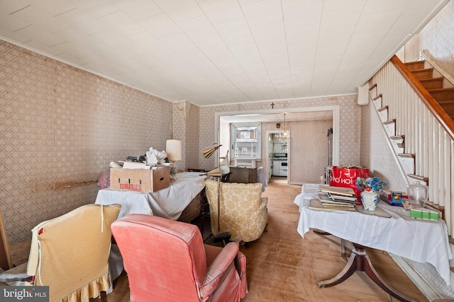 living room with ornamental molding, wood finished floors, stairway, and wallpapered walls