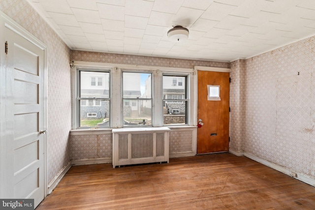 interior space with baseboards, wallpapered walls, and wood finished floors