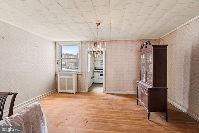 dining room featuring wallpapered walls, a notable chandelier, baseboards, and light wood-style floors