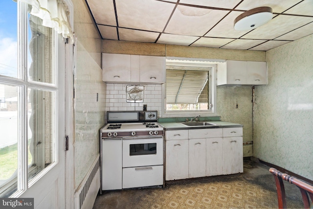 kitchen with a sink, white gas range oven, and white cabinetry