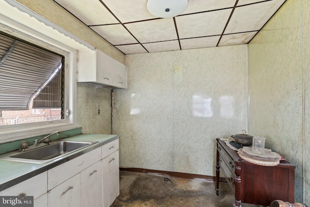 kitchen with a sink, concrete floors, and white cabinetry