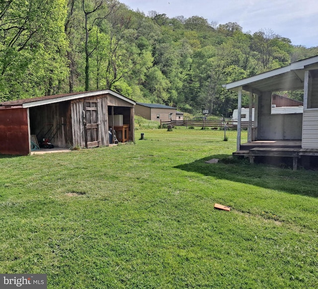 view of yard featuring a view of trees, an outbuilding, and a storage unit