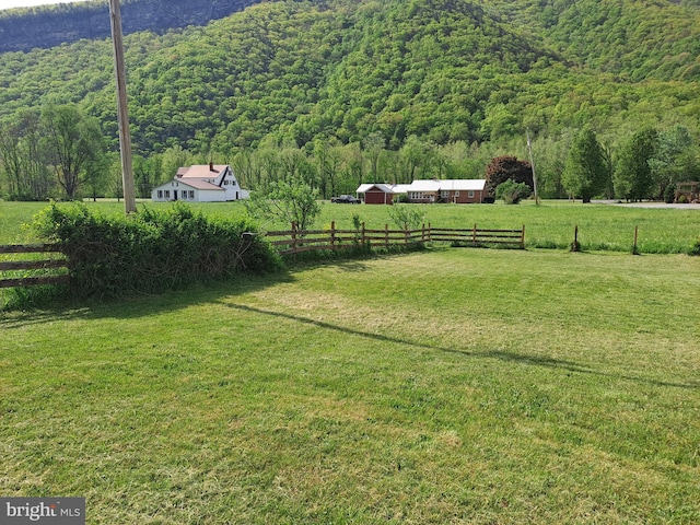 view of yard with a rural view, fence, and a wooded view