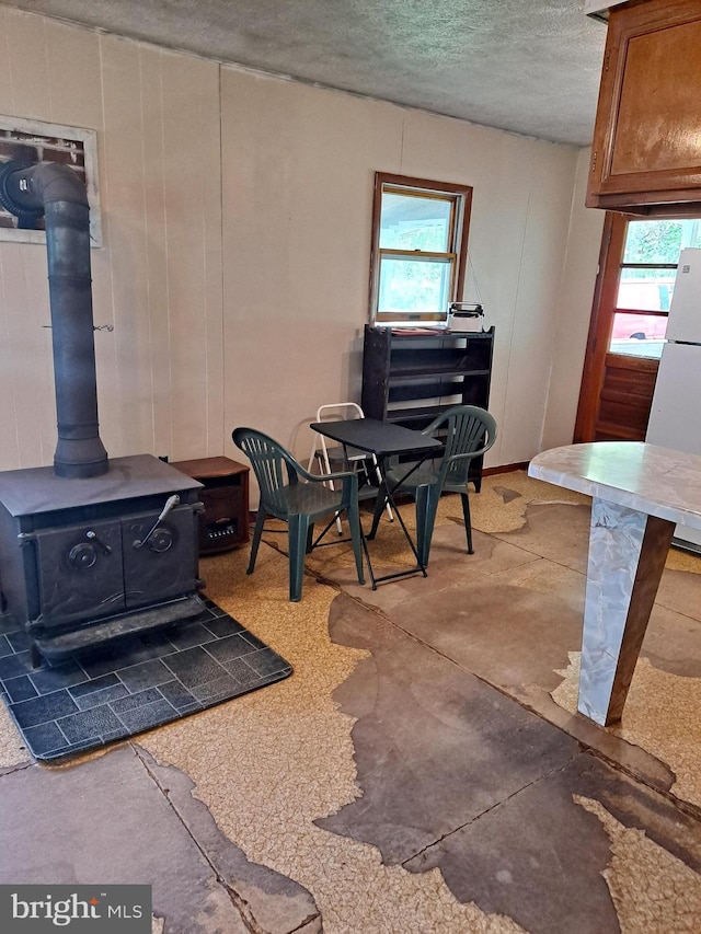 dining space with a wood stove, a textured ceiling, and a wealth of natural light