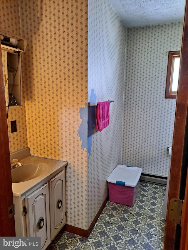 bathroom featuring vanity, baseboards, wallpapered walls, and a textured ceiling