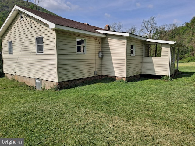 view of side of home with a lawn, a chimney, and crawl space