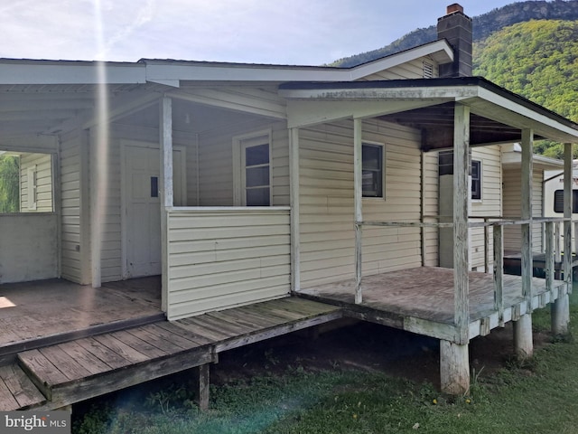 view of side of property with a deck with mountain view and a chimney