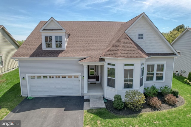 view of front facade featuring driveway, a shingled roof, and a front yard