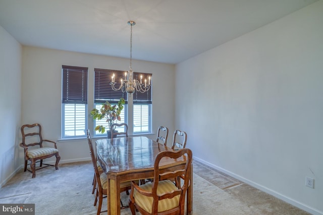 dining space with an inviting chandelier, baseboards, and light carpet