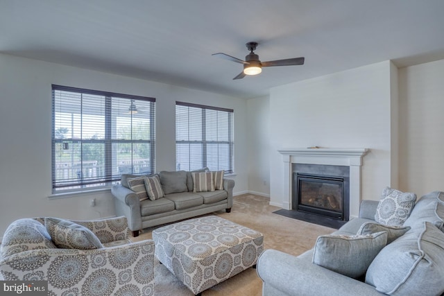 carpeted living area featuring baseboards, a fireplace with flush hearth, and ceiling fan