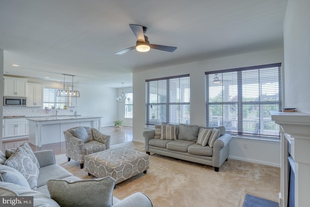 living room featuring baseboards, light carpet, ceiling fan with notable chandelier, and recessed lighting
