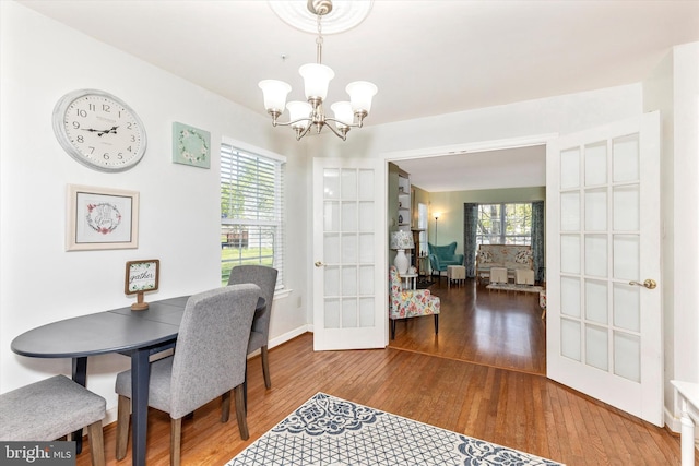 dining room featuring plenty of natural light, french doors, hardwood / wood-style floors, and a notable chandelier