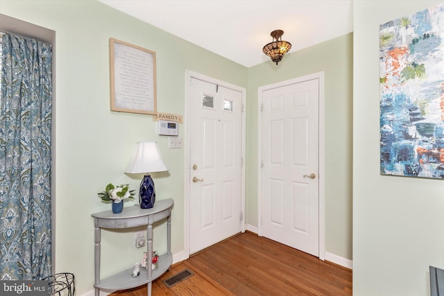 foyer entrance with visible vents, baseboards, and wood finished floors